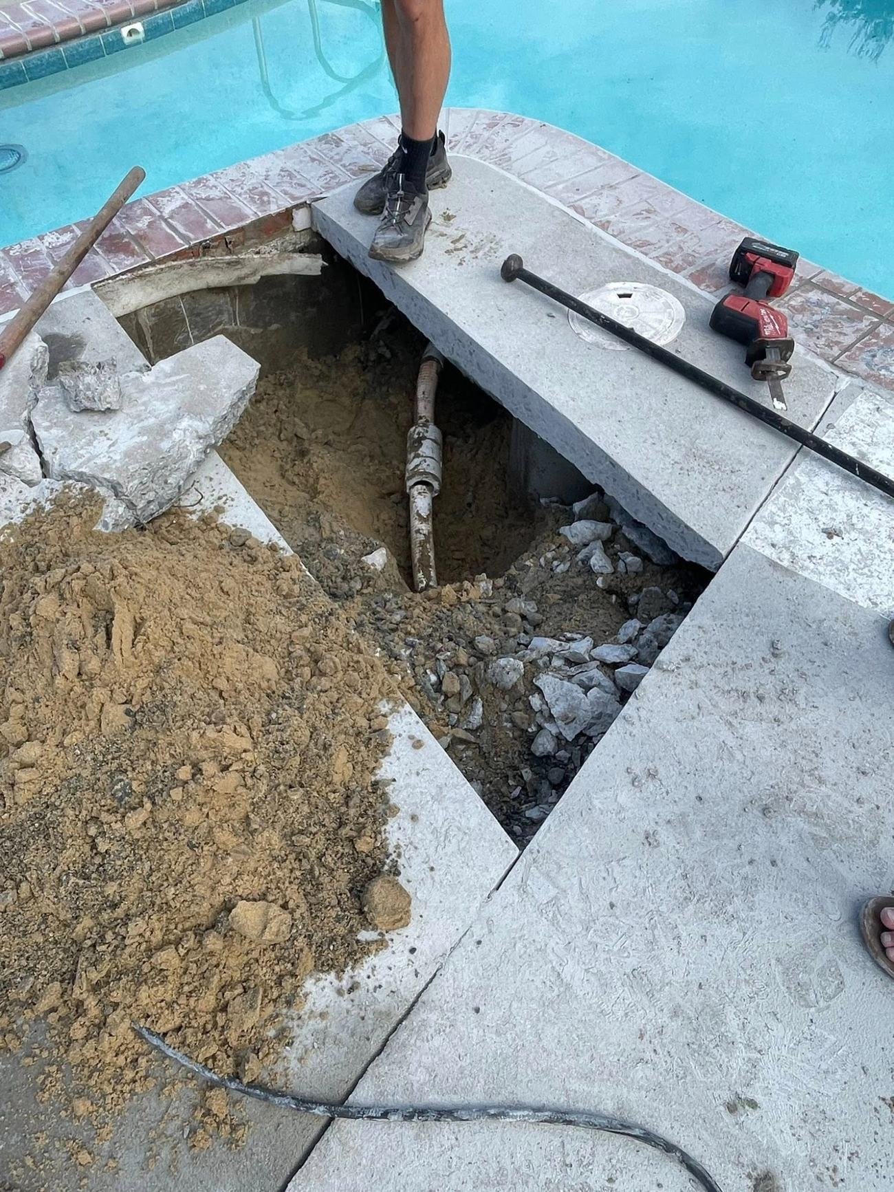 Opened pool deck with a buried pipe found during underground pool leak detection in Cathedral City
